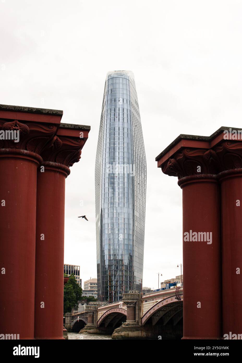 Wolkenkratzer in London zwischen zwei alten roten Brückensäulen Stockfoto