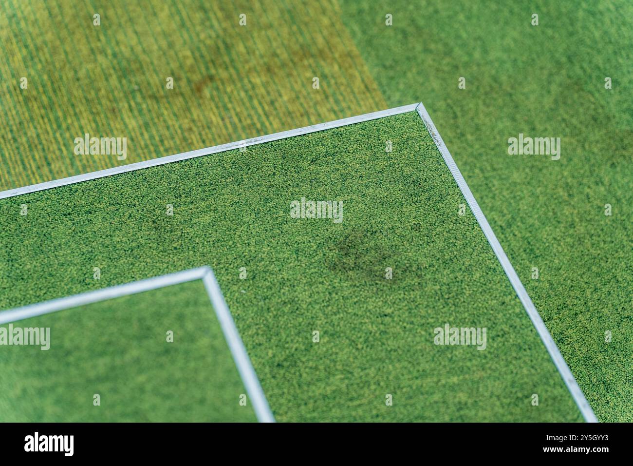 Abstraktes Tennisfeld: Grüne Wandteppiche mit weißen Kanten und schmutzigem Boden. Stockfoto