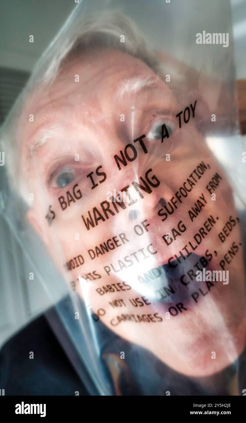 Nahaufnahme eines Reifen, älteren Mannes, der in einer transparenten Plastiktüte erstickt, mit Warnmeldung gedruckt 2024, USA Stockfoto