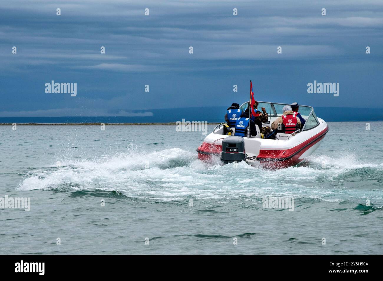 Ein weißes Boot fährt mit Vollgas am Ufer entlang. Foto von der Seite. Stockfoto