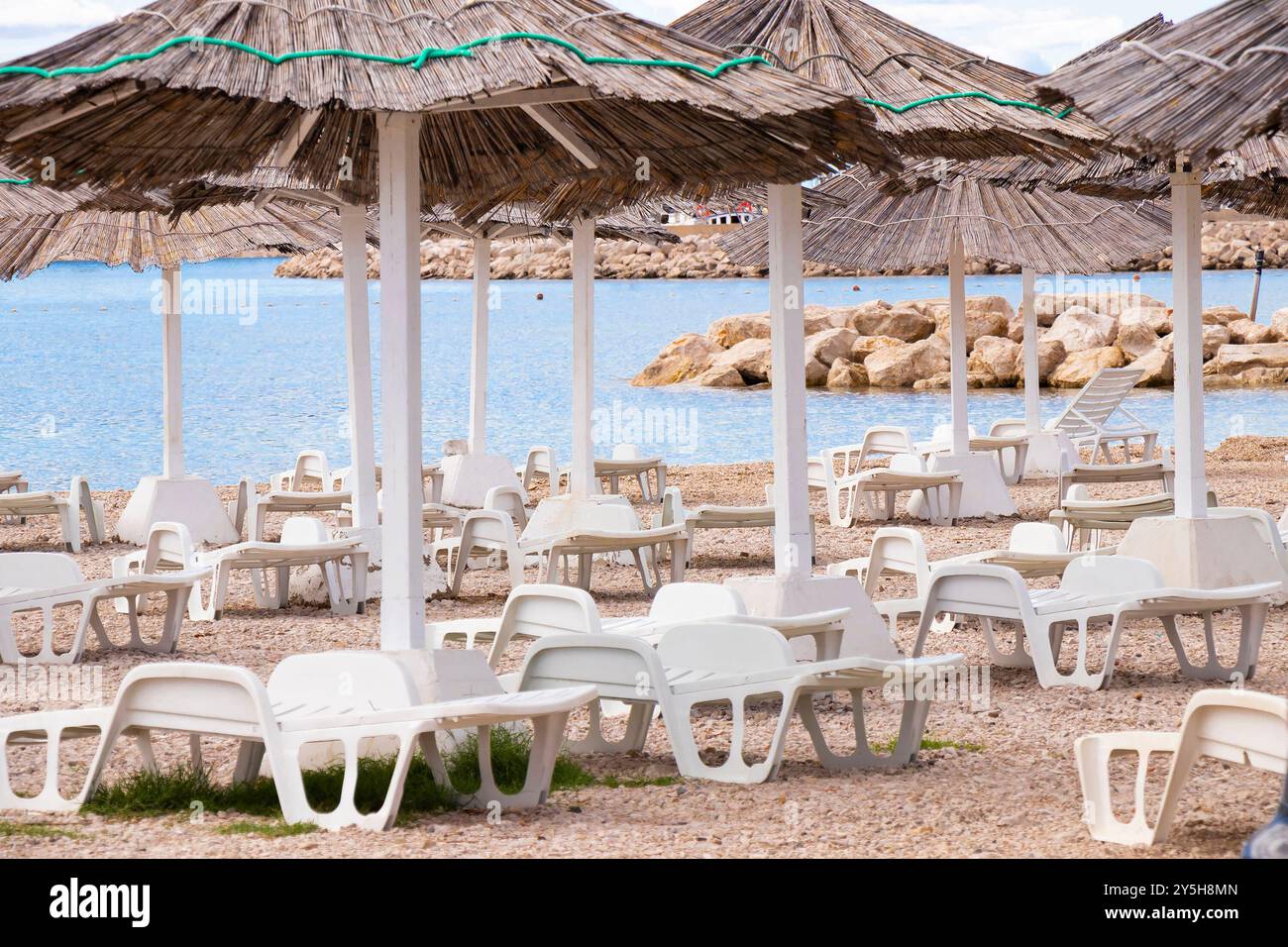 Tribunj, Kroatien - 14. September 2024: Strohschirme und Sonnenliegen stehen zur Miete bereit in Konzession am Strand, ohne Leute Stockfoto