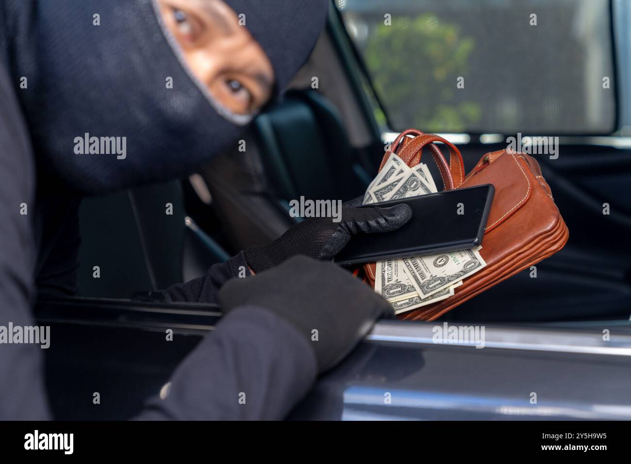Ein Dieb stiehlt Wertsachen, die im Auto liegen Stockfoto