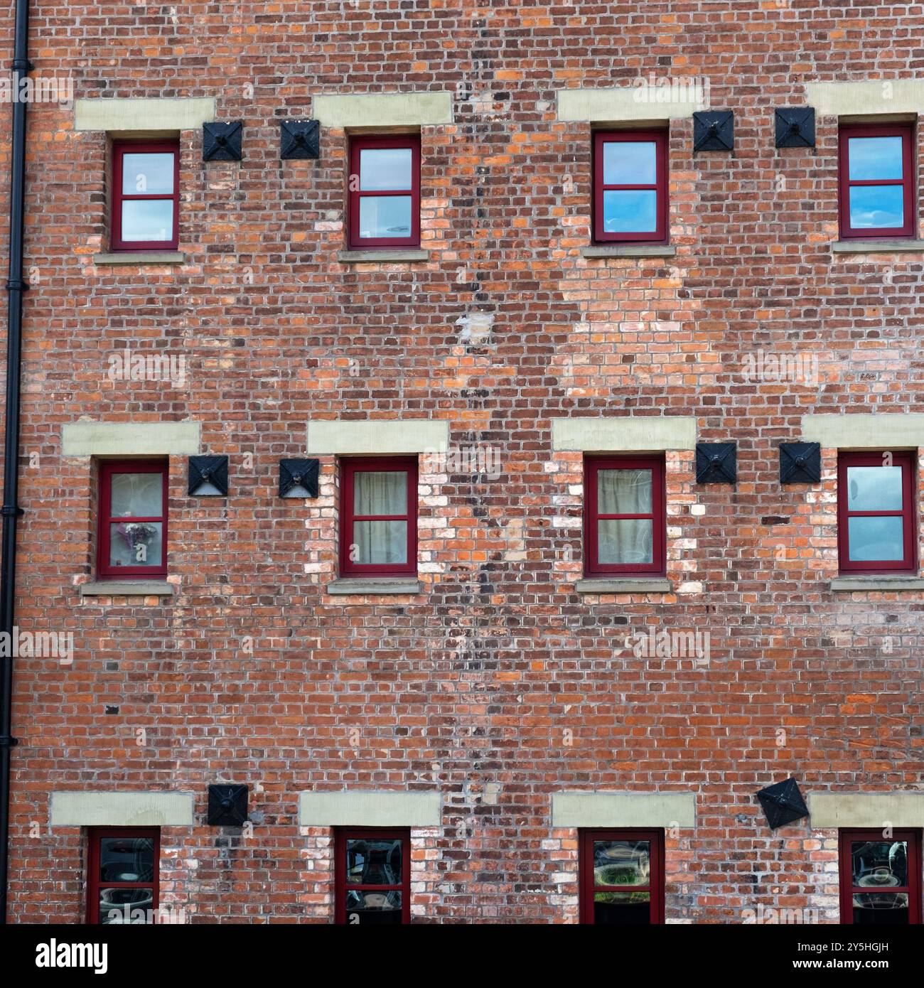 Muster aus Ziegelwerk, Wohnungsfenstern und strukturellen Stützen in einem viktorianischen Lagerhaus am Hafen, das für das städtische Leben restauriert wurde Stockfoto