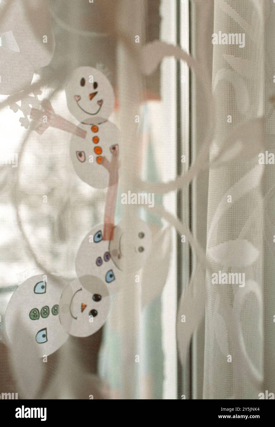 Farbenfrohe Schneemanndekorationen mit fröhlichen Gesichtern zieren das Fenster, die den Geist des Winters einfangen und dem Zuhause einen verspielten Touch verleihen Stockfoto