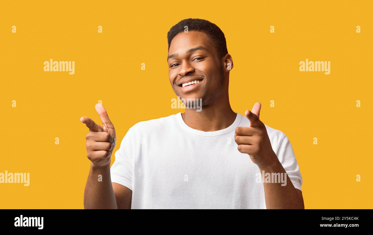 Aufgeregter schwarzer Kerl, der Sie über orangefarbenem Hintergrund wählt Stockfoto
