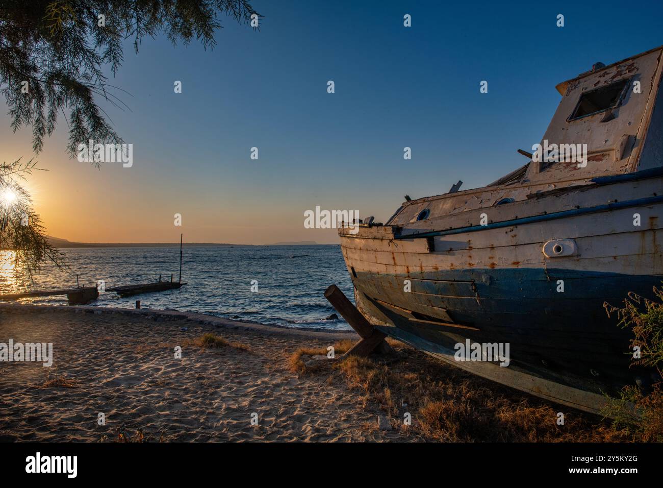 Ein verrottetes Fischerboot an der Küste bei Sonnenuntergang in der Nähe von Malia auf Kreta, Griechenland Stockfoto