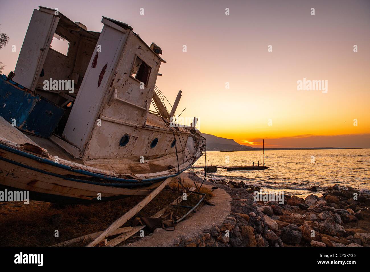 Ein verrottetes Fischerboot an der Küste bei Sonnenuntergang in der Nähe von Malia auf Kreta, Griechenland Stockfoto