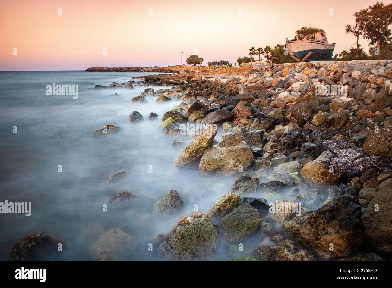 Ein verrottetes Fischerboot an der Küste bei Sonnenuntergang in der Nähe von Malia auf Kreta, Griechenland Stockfoto