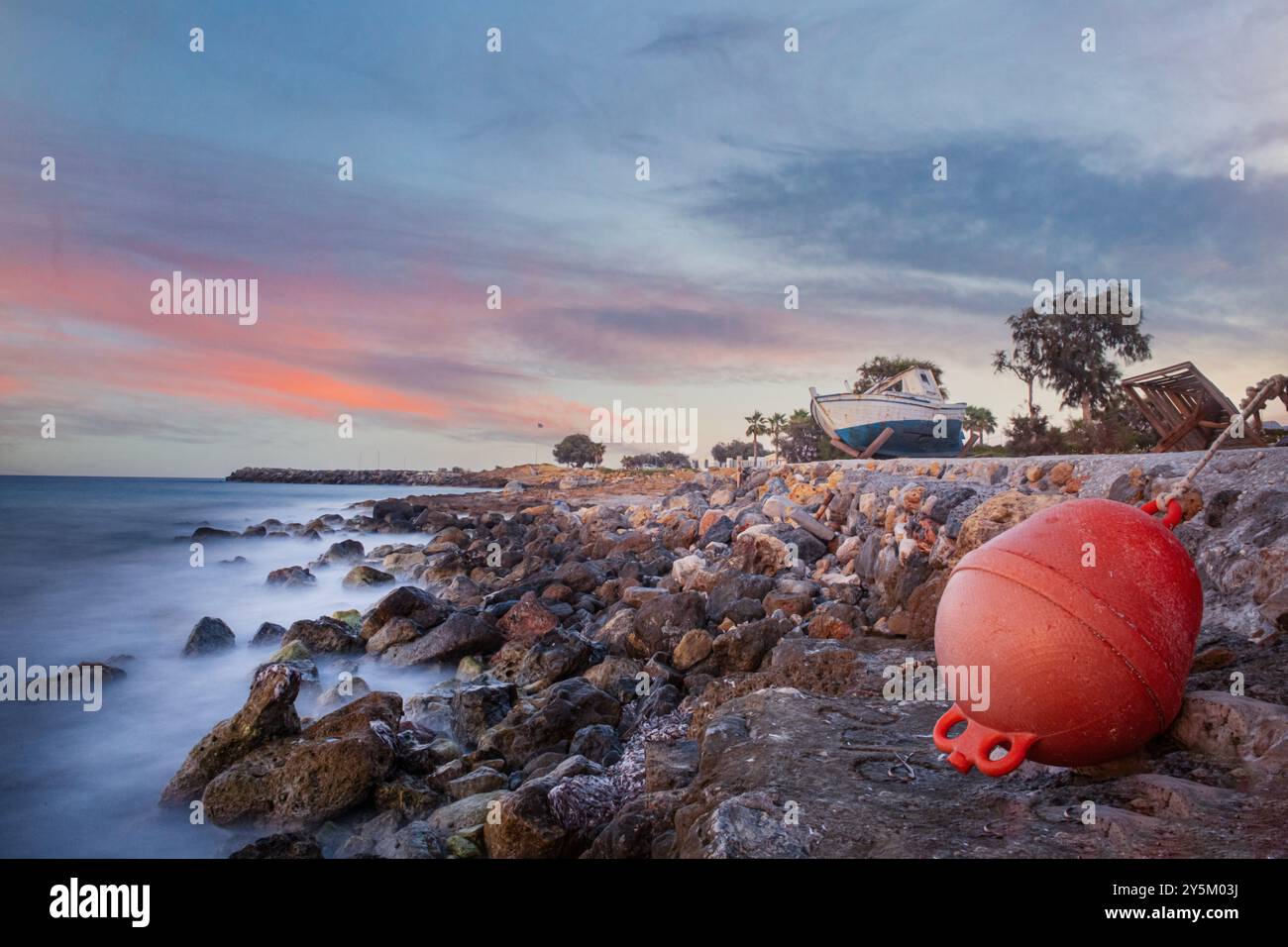 Ein verrottetes Fischerboot an der Küste bei Sonnenuntergang in der Nähe von Malia auf Kreta, Griechenland Stockfoto