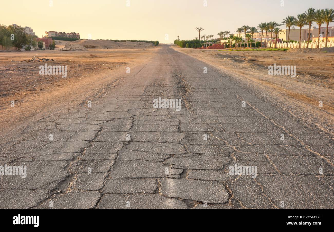 Leere Wüstenstraße bei Sonnenuntergang, Schwerpunkt auf Asphalt, Ägypten. Stockfoto