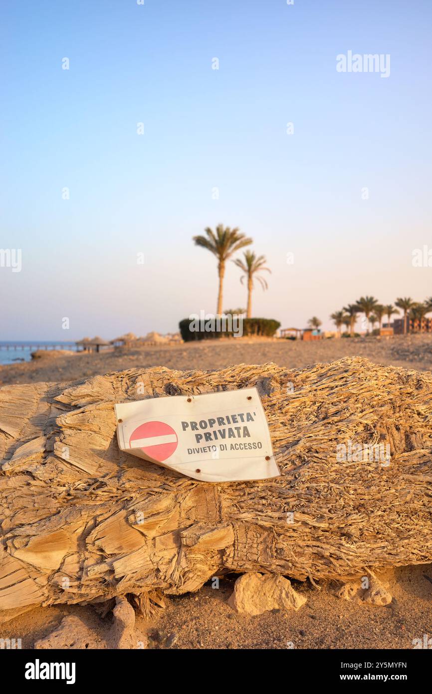 Schild mit privatem Grundstück an einem Palmenstamm an einem Strand bei Sonnenuntergang, Marsa Alam, Ägypten. Stockfoto