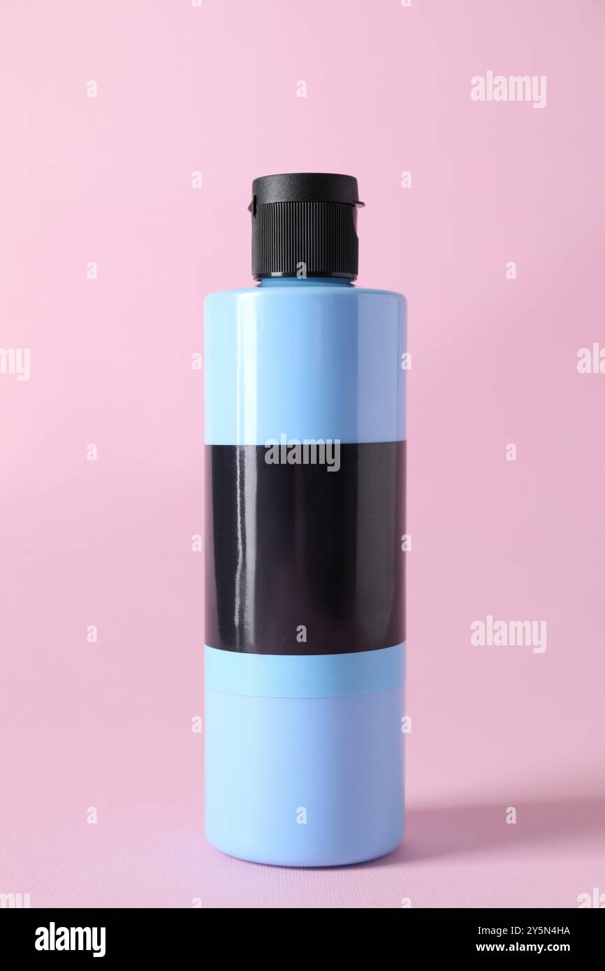 Hellblaue Acrylfarbe in der Flasche auf rosa Hintergrund Stockfoto