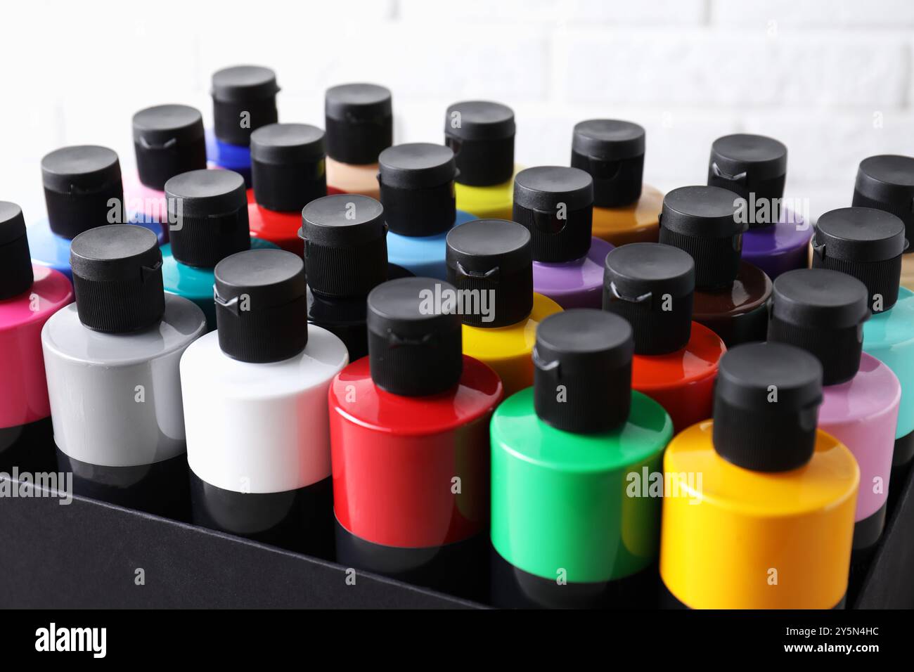 Acrylfarben in verschiedenen Farben in Flaschen vor weißem Hintergrund, Nahaufnahme Stockfoto