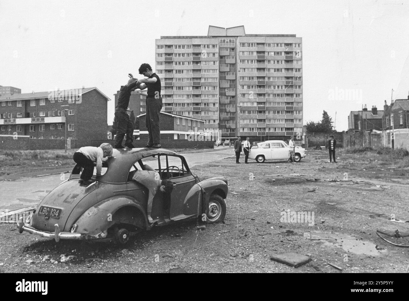 DIE JUGENDLICHEN SPIELEN AUF EINEM ALTEN AUTO AUF DEM MÜLLBODEN VOR PICKWICK HOUE, PORTSMOUTH. BILD MIKE WALKER 1966 Stockfoto