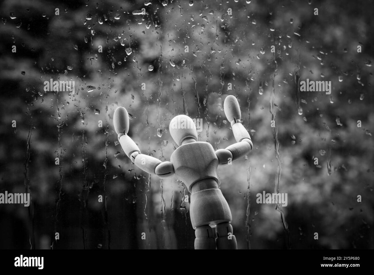 Psychische Gesundheit Problemkonzept. Hölzerne Schaufensterpuppe am Fenster im Regen. Traurigkeit, Einsamkeit, Depression oder saisonale affektive Störung Stockfoto