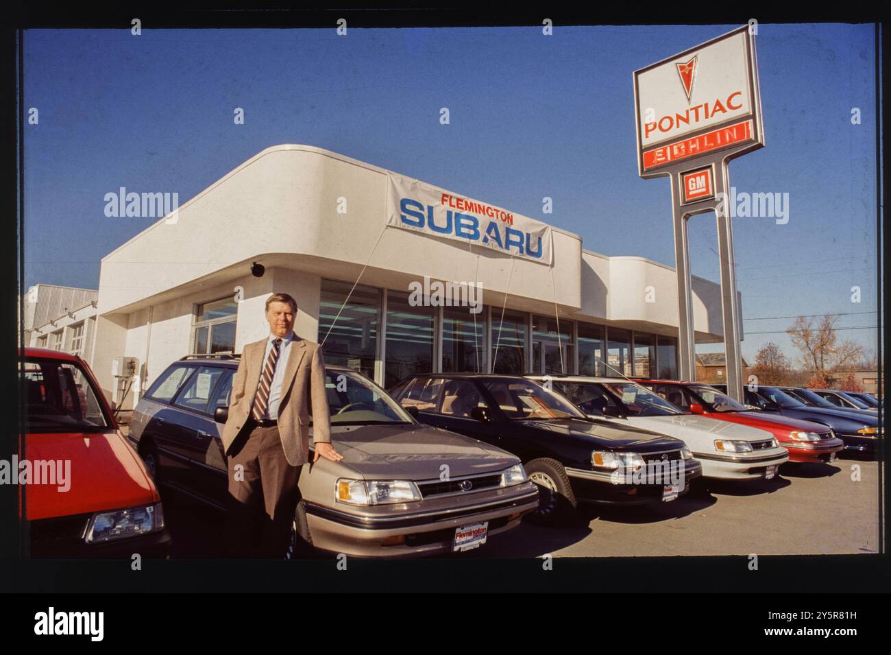 In den späten 1980er Jahren posierte ein Verkäufer vor dem Flemington Subaru-Pontiac Händlerbetrieb in Trenton, New Jersey Das Los verfügt über eine Reihe von Subaru-Modellen, darunter beliebte Wagen, die für ihre Funktionalität und Langlebigkeit bekannt sind, sowie Pontiac-Fahrzeuge, was einen Zweimarken-Händler hervorhebt. Stockfoto