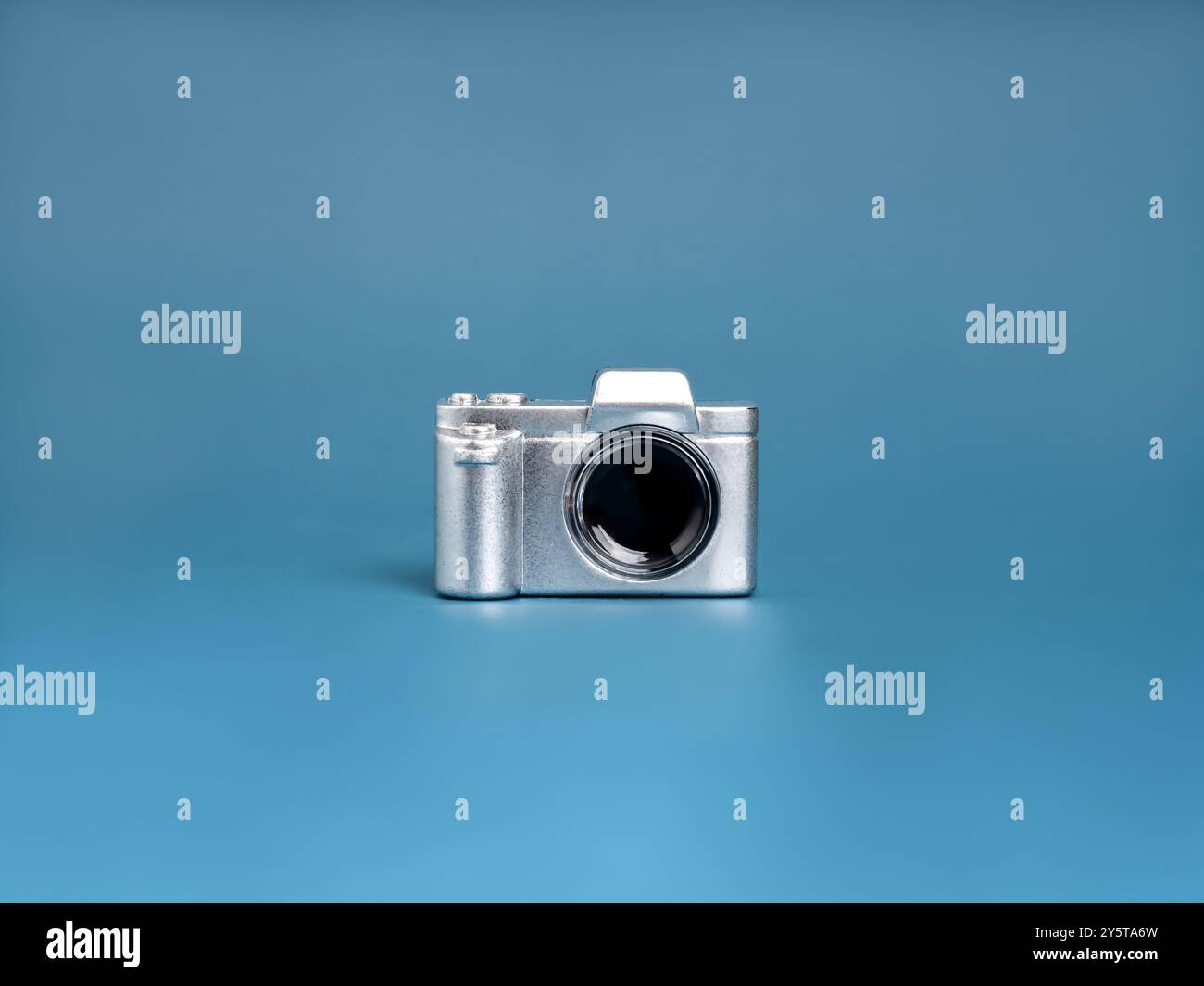 Glänzendes silbernes Vintage-Kameraspielzeug isoliert auf blauem Hintergrund, minimalistisch. Fotoobjektwerkzeuge, Ermittler, Detektiv, stylischer Fotograf Stockfoto
