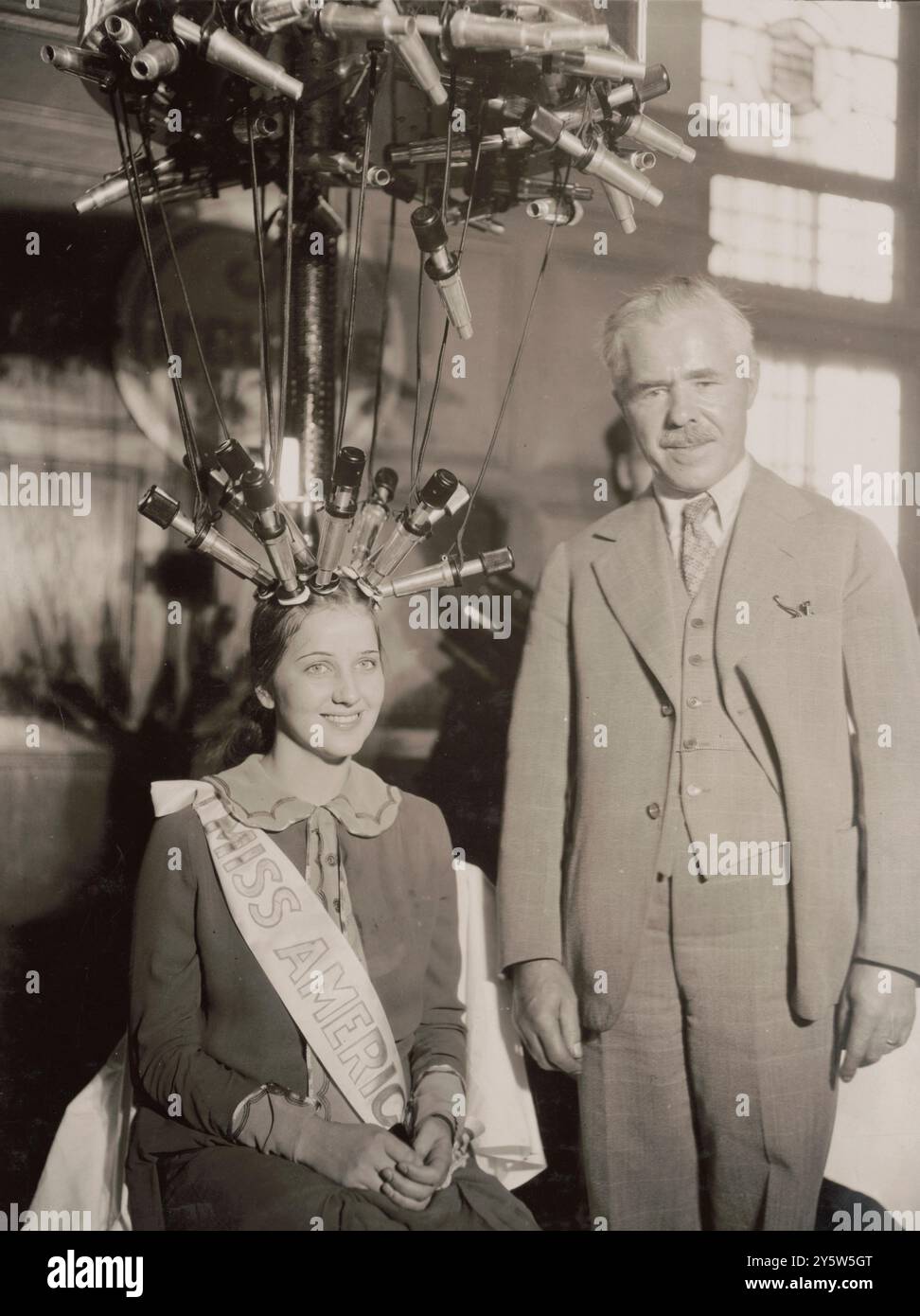 Brüllende Zwanziger. Miss America erhält eine permanente Welle. Oktober 1926 Norma Smallwood, Miss America 1926, sitzend, mit Haaren an elektrischen Dauerwellen-Geräten befestigt, mit Mann neben ihr. Stockfoto