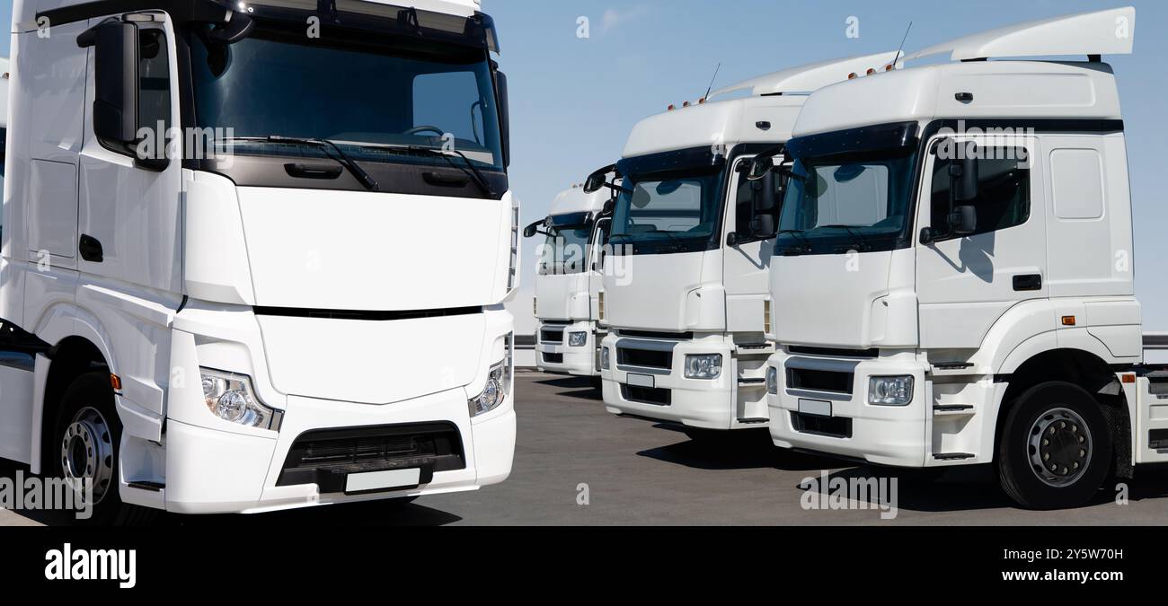 Flotte von weißen Sattelzugmaschinen in Reihe. Stockfoto