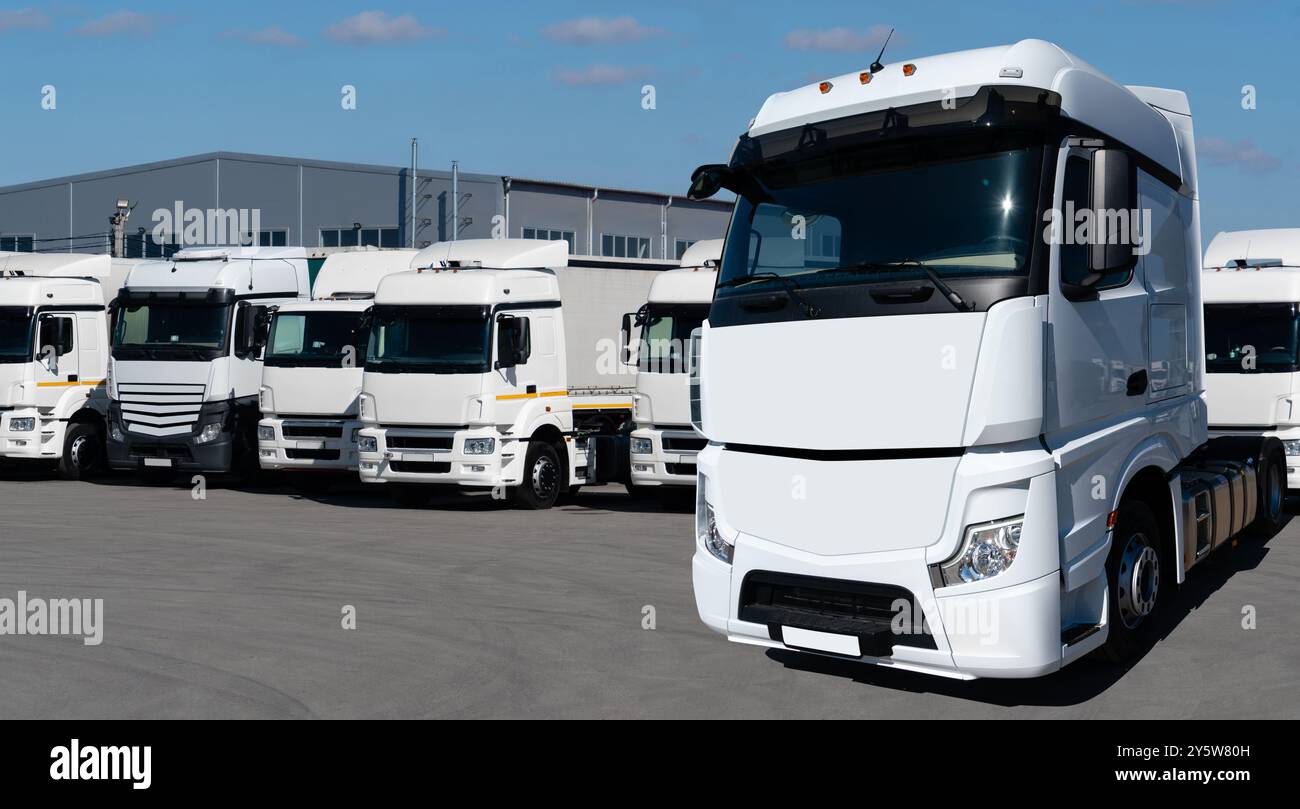 Flotte von weißen Sattelzugmaschinen in Reihe. Stockfoto