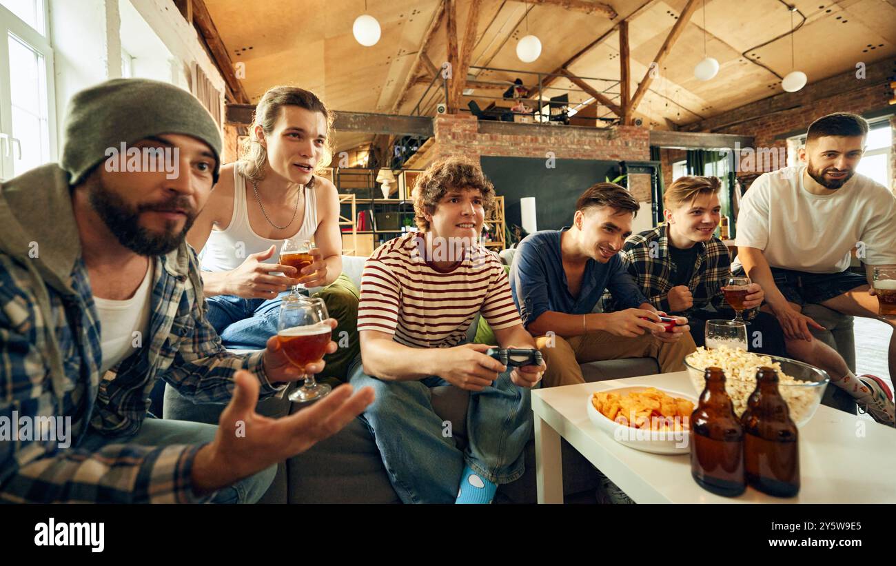 Der Nervenkitzel des Spiels übernimmt die Macht, wenn sich die Jungs hineinlehnen und alles geben. Die perfekte Mischung aus Spannung und Lachen, während sie Getränke teilen und spielen. Stockfoto