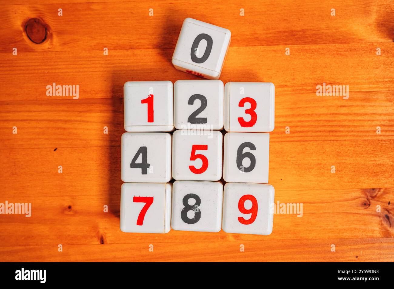 Zahlen lernen und mathematische Berechnung, Draufsicht auf Plastikwürfel mit Zahlen auf Holztisch, direkt darüber Stockfoto