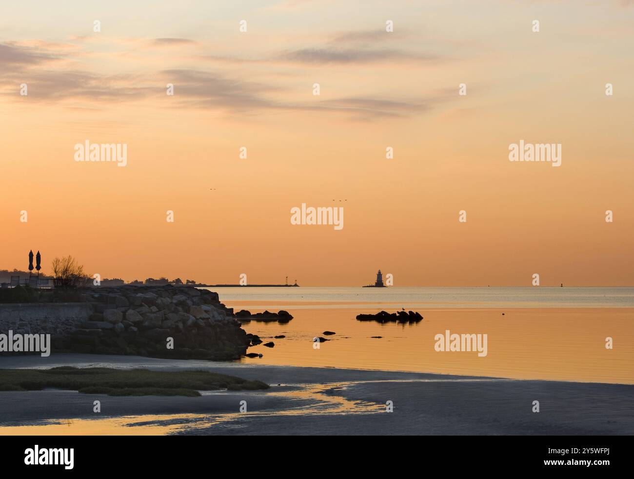 Der Sonnenaufgang über der Küste von Connecticut wirft ein orangefarbenes Licht. Stockfoto