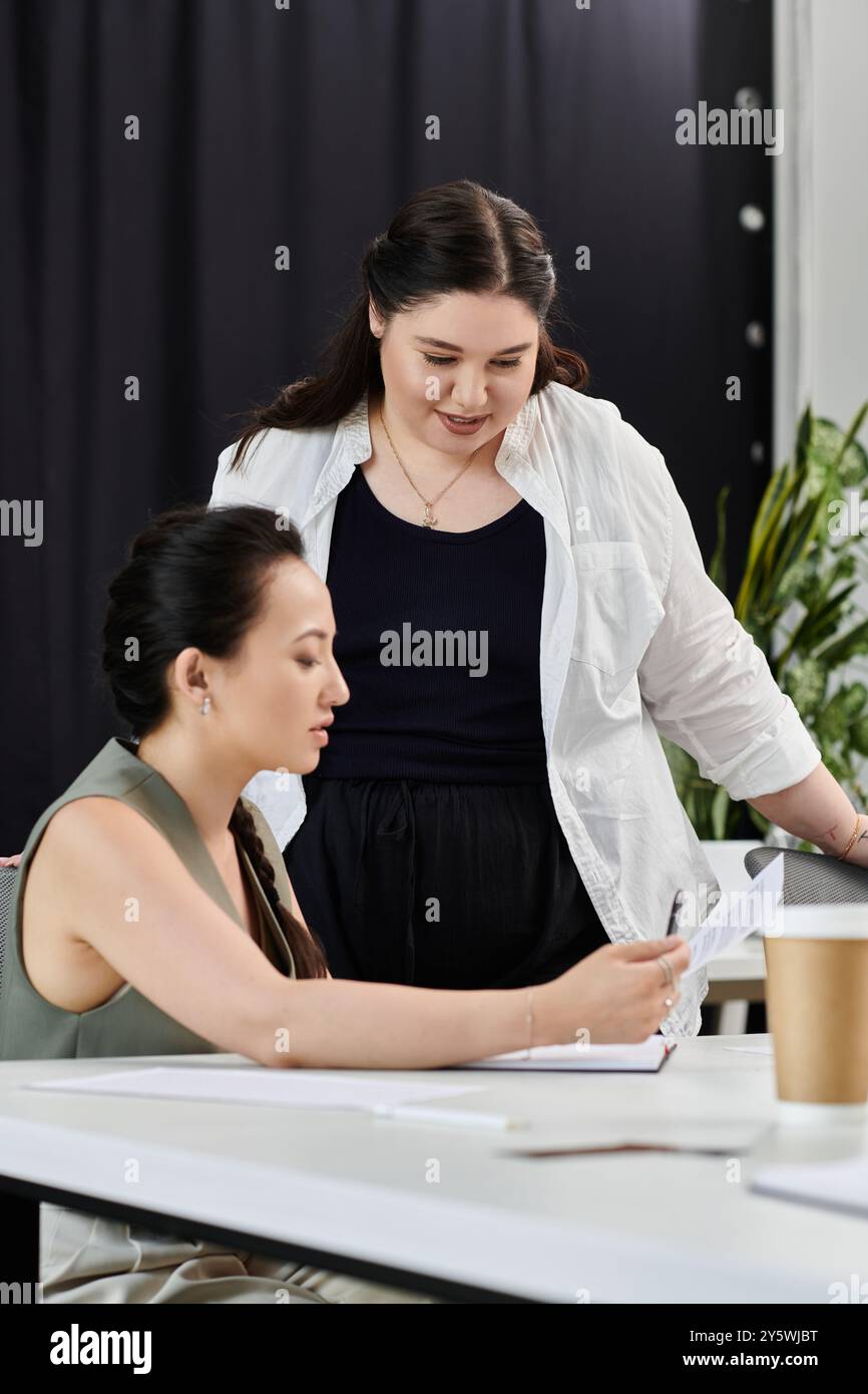 Zwei professionelle Frauen diskutieren und prüfen Dokumente in einem modernen Büroarbeitsplatz. Stockfoto