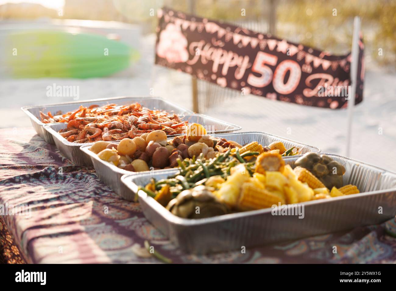 Picknicktisch im Freien, dekoriert für eine Geburtstagsfeier mit einem „Happy 50th Birthday“-Banner und Tabletts mit köstlichen Speisen in der warmen Sonne, Florida, USA Stockfoto