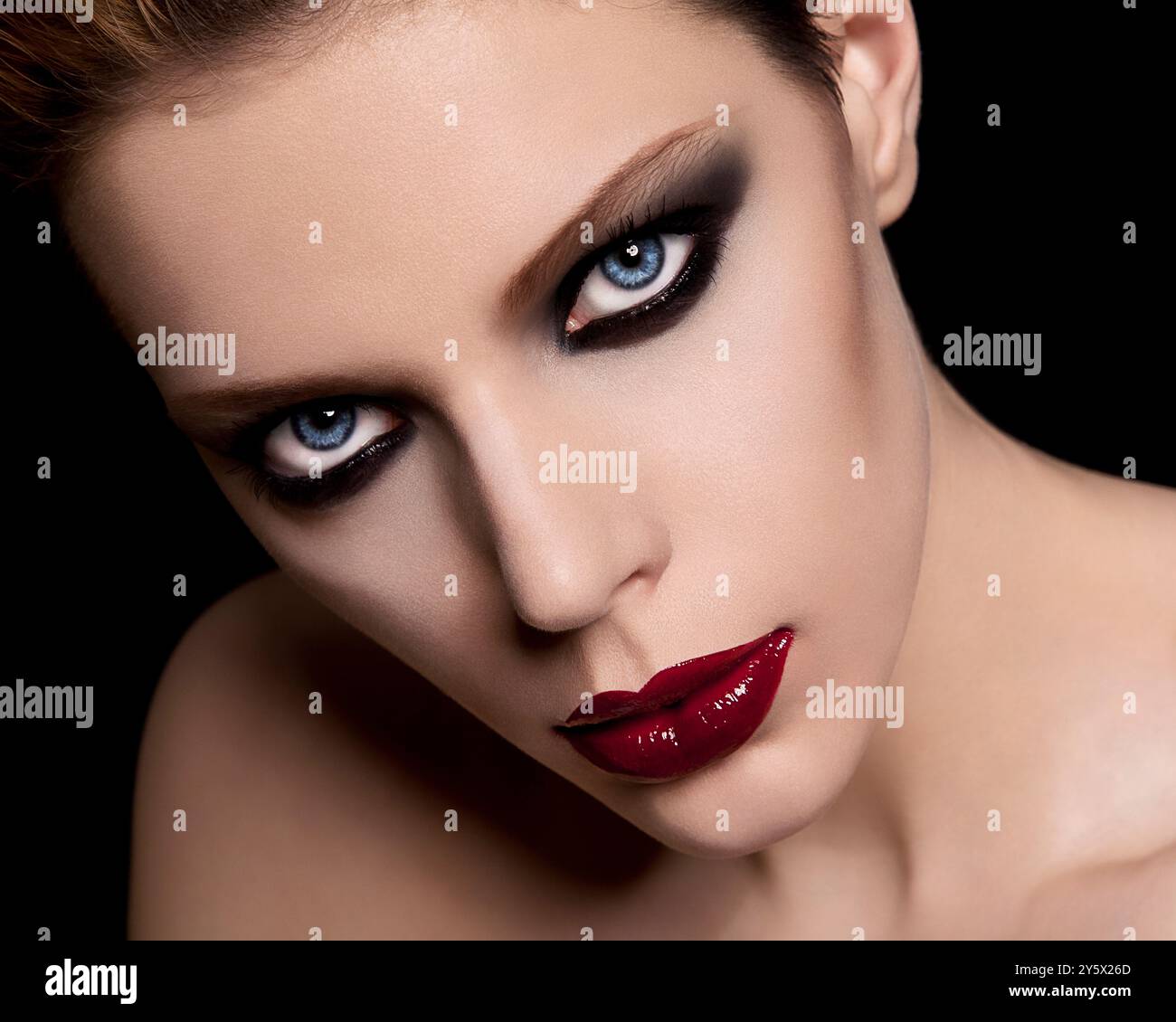 Porträt einer Frau in Nahaufnahme mit dramatischem rotem Lippenstift und rauchiger Augen-Make-up vor schwarzem Hintergrund. Stockfoto Porträt einer Frau in Nahaufnahme mit dramatischem rotem Lippenstift und rauchiger Augen-Make-up vor schwarzem Hintergrund. Stockfoto