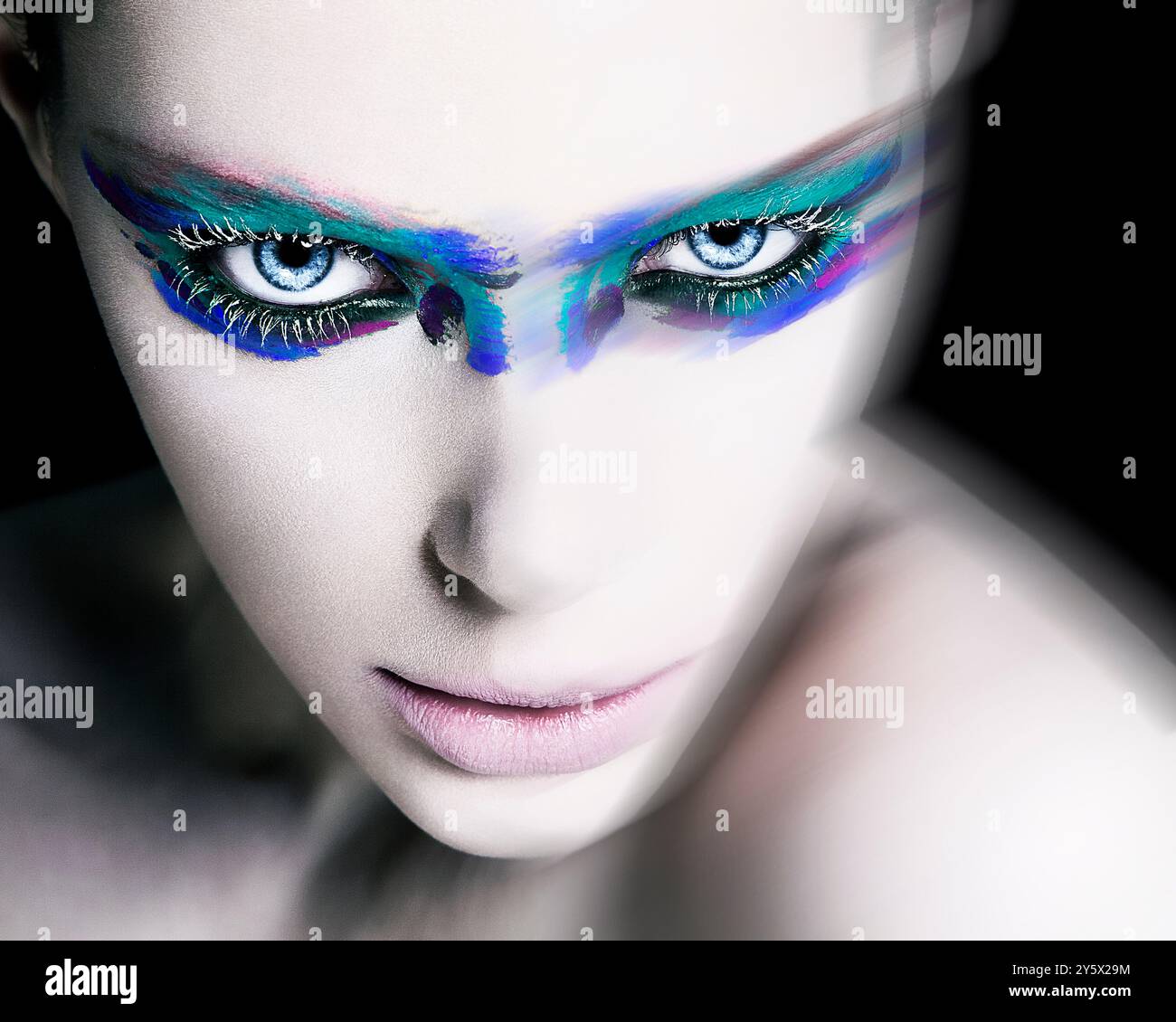 Nahaufnahme einer Person mit auffälligem blau-violettem Augen-Make-up und intensivem Blick auf schwarzem Hintergrund. Stockfoto Nahaufnahme einer Person mit auffälligem blau-violettem Augen-Make-up und intensivem Blick auf schwarzem Hintergrund. Stockfoto