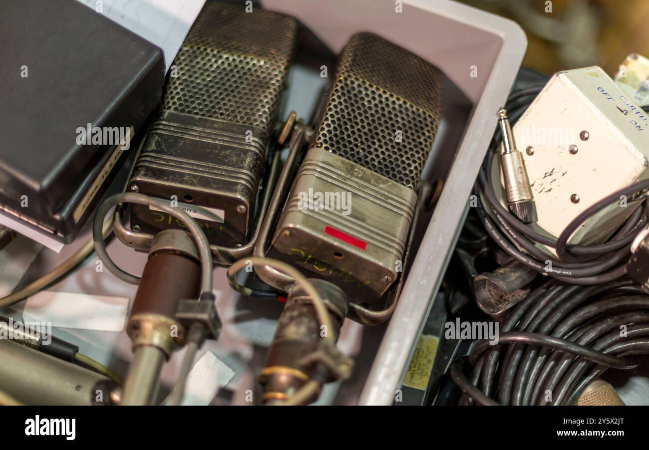 Zwei Vintage-RCA-Mikrofone mit angeschlossenen Kabeln, die zwischen Audiogeräten eingebettet sind. Stockfoto