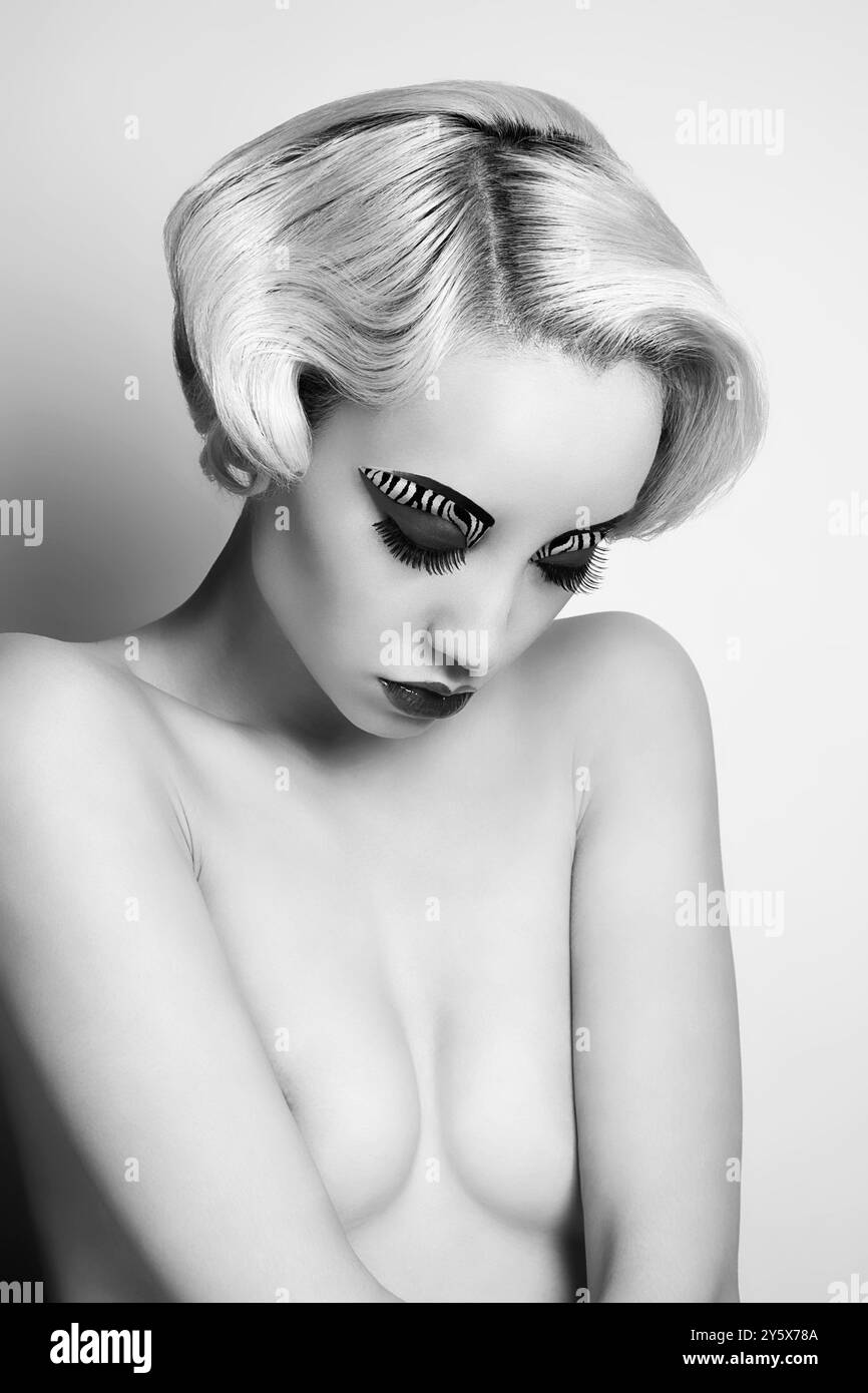 Schwarz-weißes Porträt einer Frau mit auffälligem Augen-Make-up und Vintage-Frisur. Stockfoto