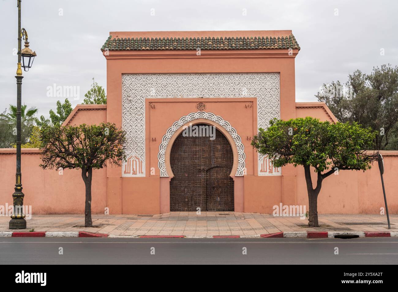 Holztür in Marrakesch, Marokko. Marokkanisches geschlossenes Torbogen in Terrakotta-Steinmauer mit islamischen Ornamenten Stockfoto
