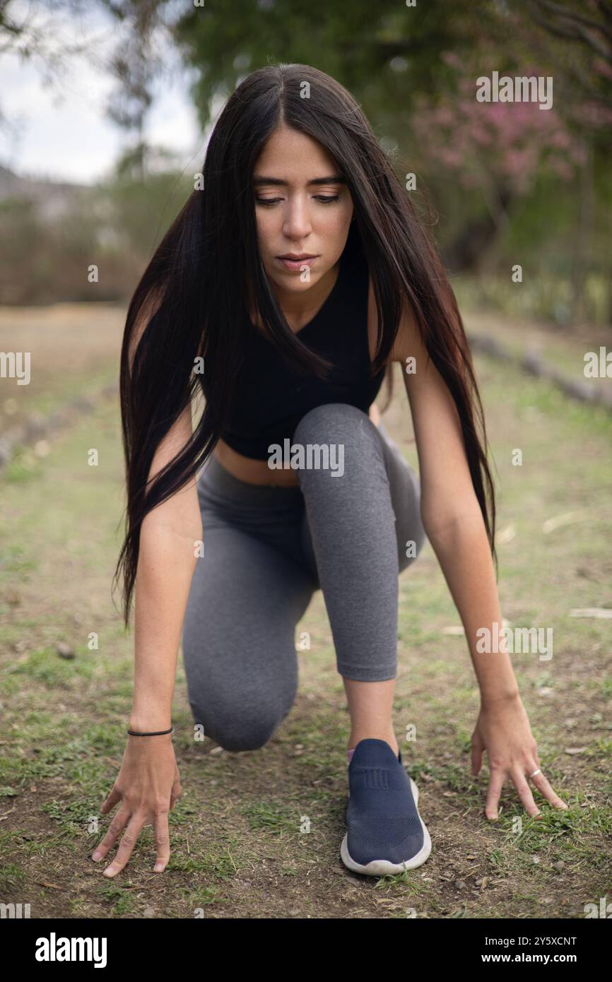 Sonniger Tag mit junger Frau am Ausgangspunkt, laufender Starthaltung, gesunder Lebensstil, weibliches Model mit Sportbekleidung Stockfoto