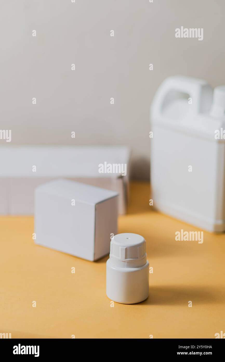 Ein sauberes, minimalistisches Arrangement mit weißen Plastikflaschen und Kartonschachteln auf neutralem Hintergrund. Perfekt für die Präsentation von Verpackungsdesign A Stockfoto