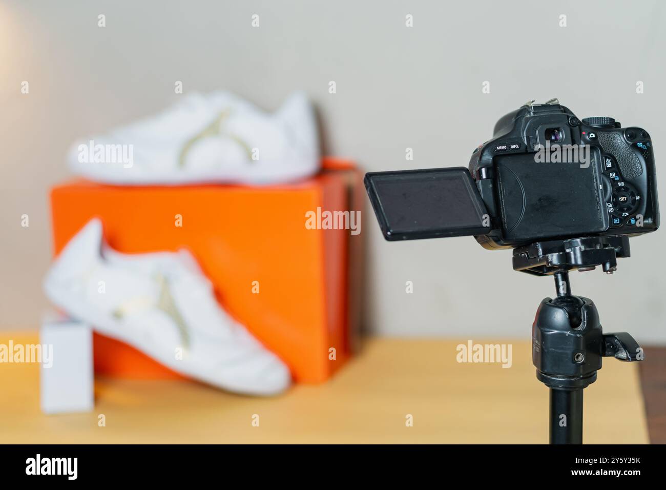 Eine Spiegelreflexkamera auf einem Stativ, die ein Paar stylische Sneaker für ein Produktfoto aufnimmt. Perfektes Image für E-Commerce- oder Modemarketing-Zwecke. Stockfoto