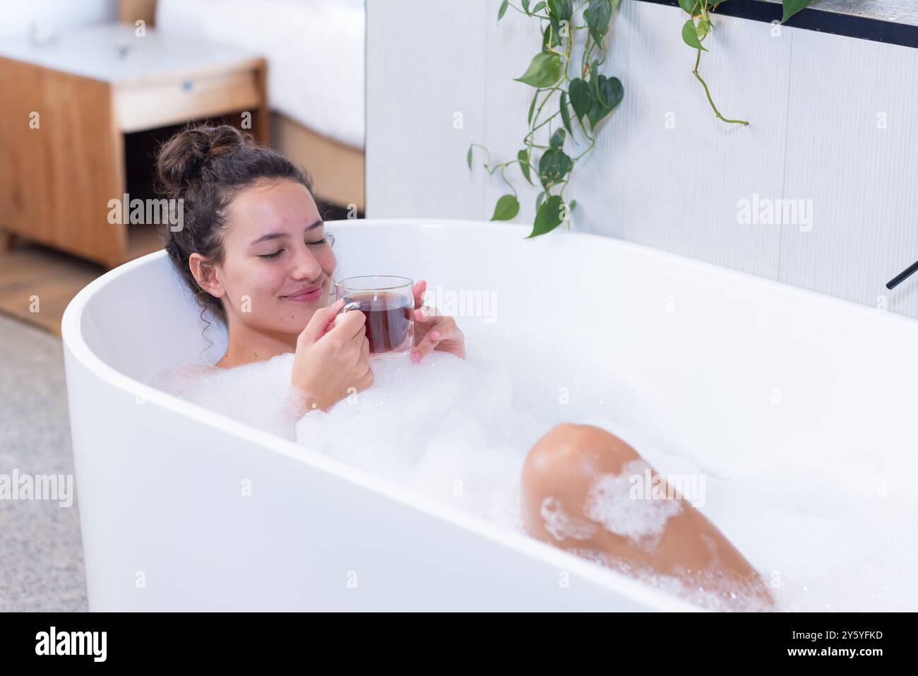 Entspannen Sie sich im Sprudelbad, Frau genießt heißes Getränk in der Badewanne Stockfoto