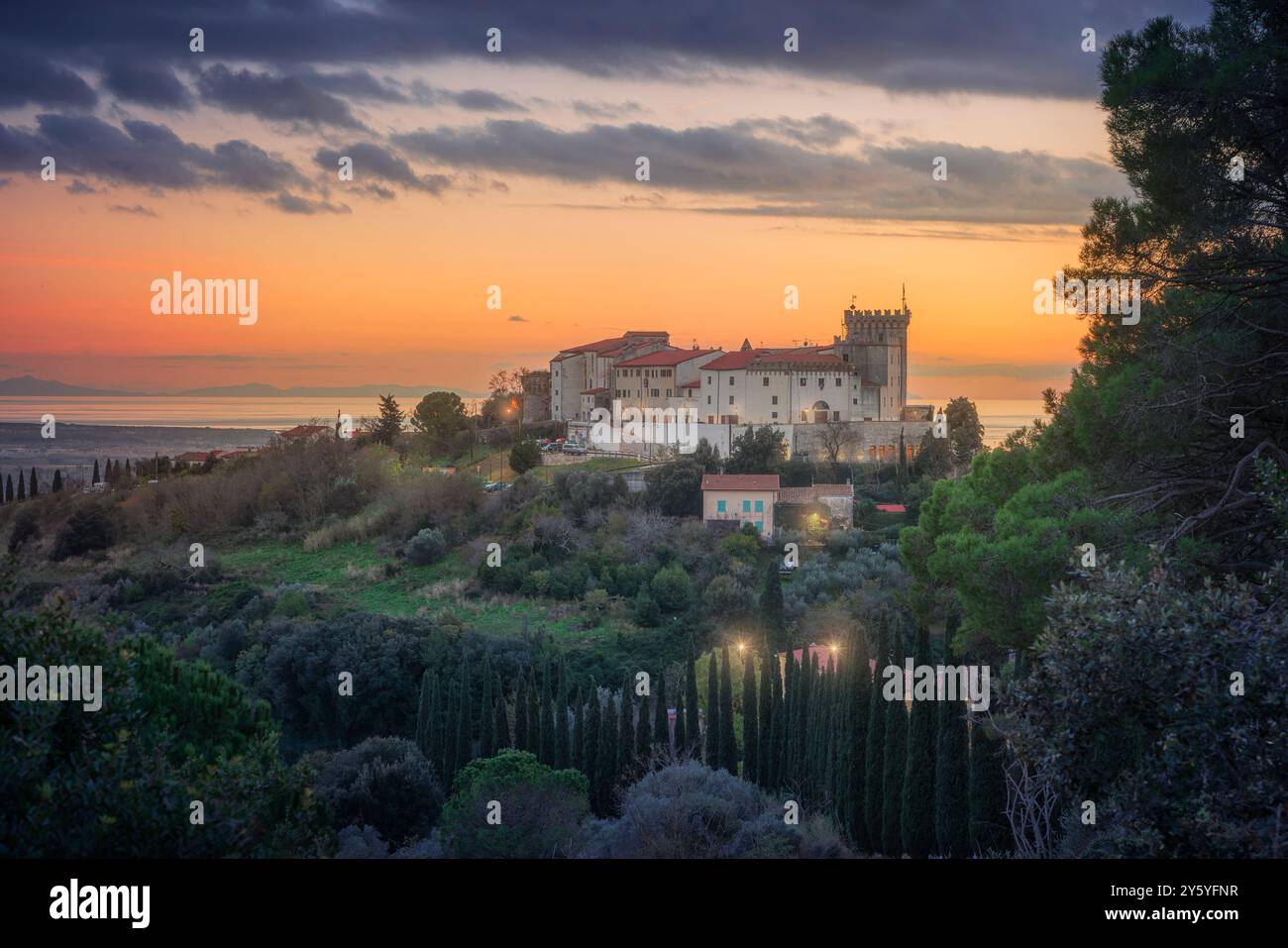 Blick von oben auf die Stadt Rosignano Marittimo und die Burg. Meer im Hintergrund bei Sonnenuntergang. Toskana, Italien Stockfoto