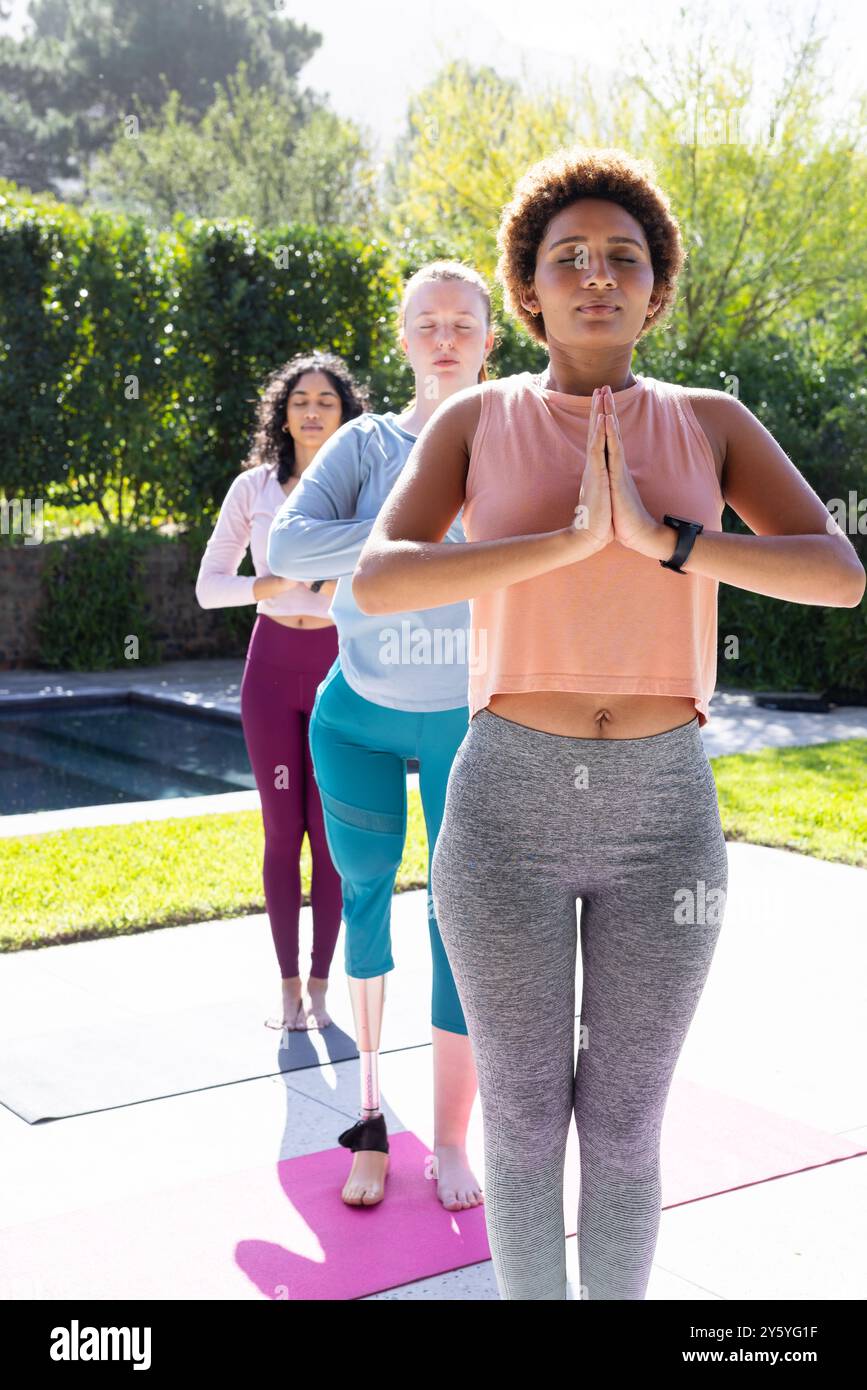 Yoga im Freien üben, verschiedene Freundinnen stehen in Baumpositionen auf Yogamatten Stockfoto