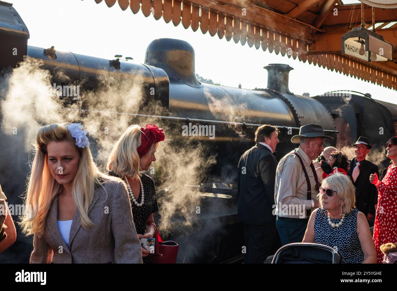 Sheringham, Norfolk, Vereinigtes Königreich - 21. SEPTEMBER 2024: Frauen in Vintage-Kleidung der 1940er-Jahre gehen am Wochenende der 1940er vor der Dampflokomotive Stockfoto