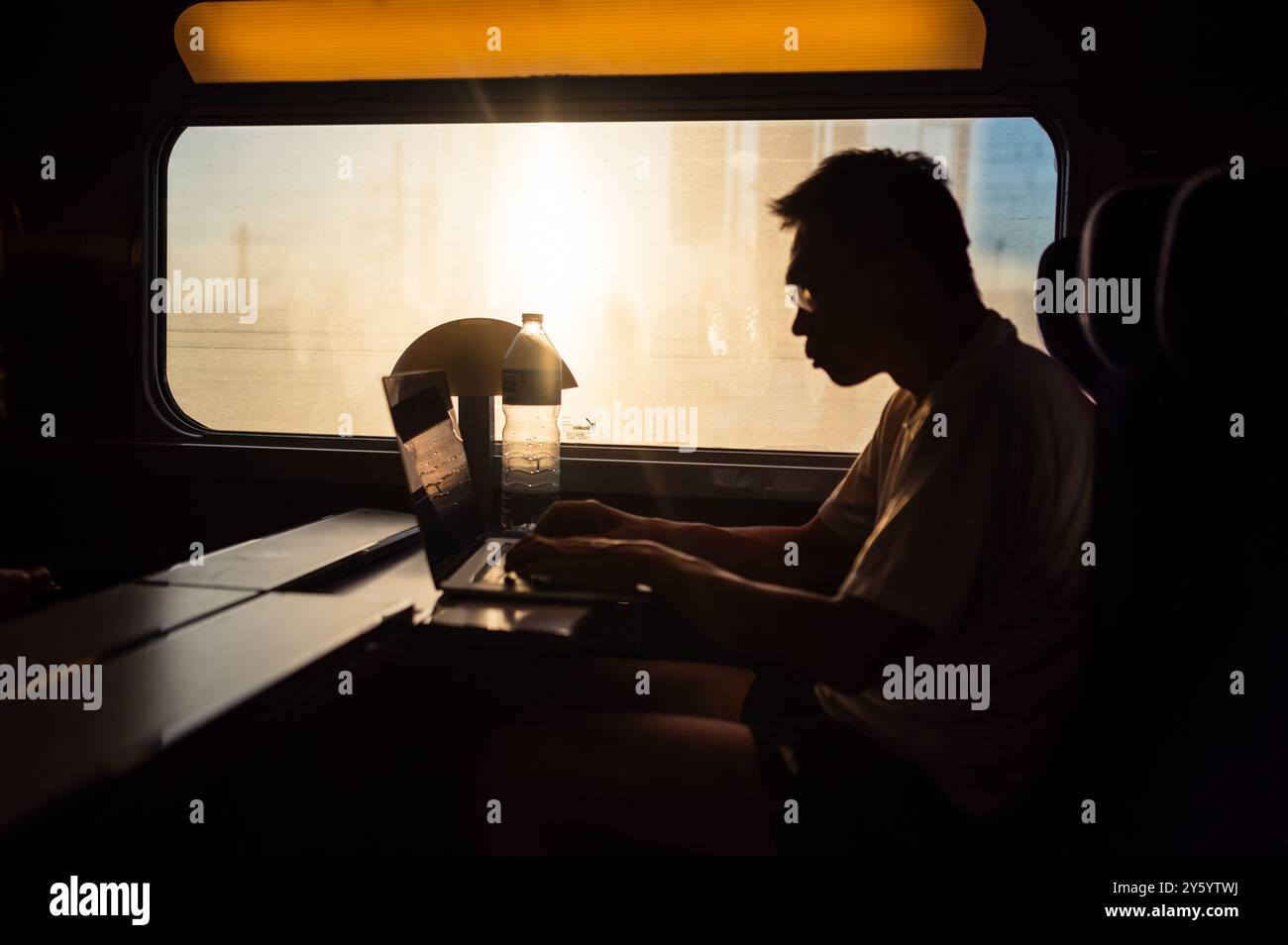 Silhouette eines Mannes, der mit seinem Laptop im Hochgeschwindigkeitszug AVE in Spanien arbeitet Stockfoto