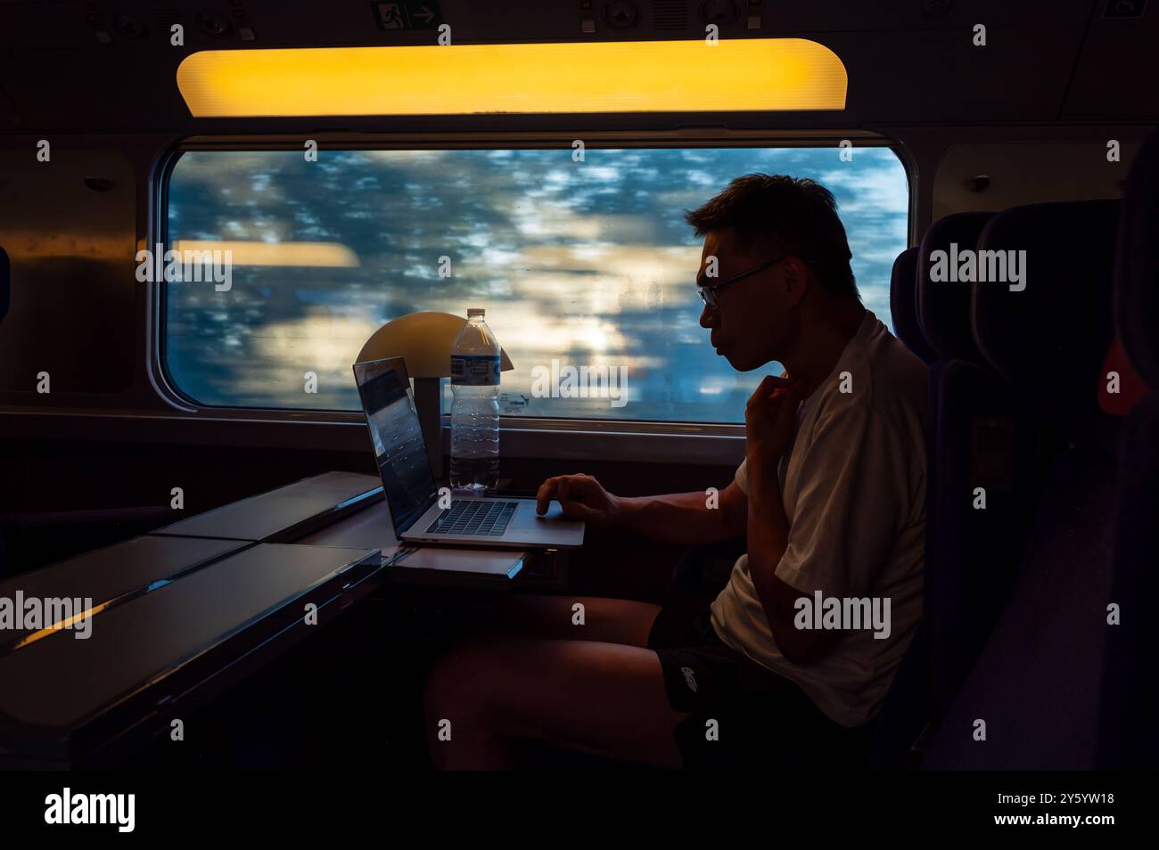 Silhouette eines Mannes, der mit seinem Laptop im Hochgeschwindigkeitszug AVE in Spanien arbeitet Stockfoto