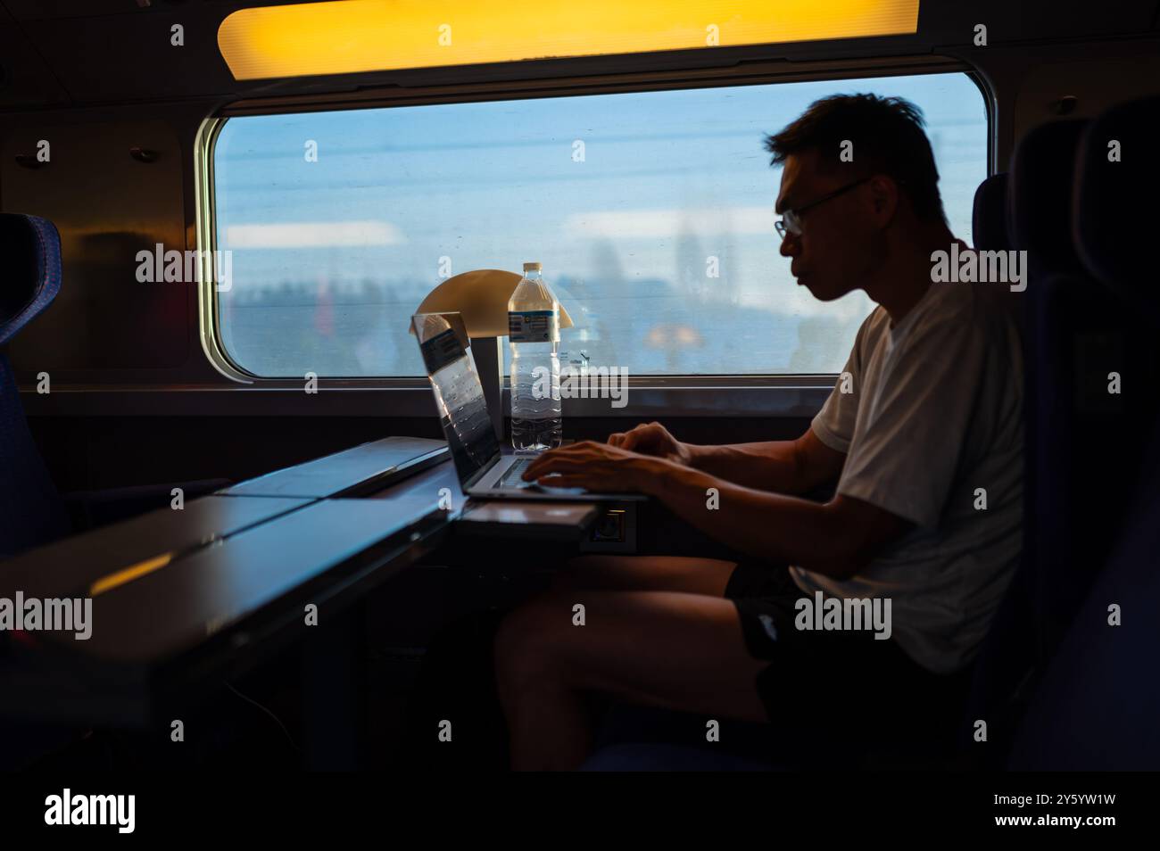 Silhouette eines Mannes, der mit seinem Laptop im Hochgeschwindigkeitszug AVE in Spanien arbeitet Stockfoto