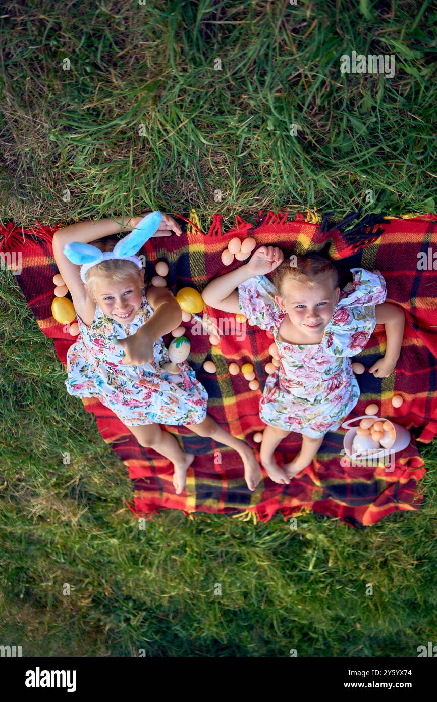 Kleine Mädchen, Schwestern, spielen auf einer Picknickdecke mit Eiern nach der Ostereierjagd Stockfoto