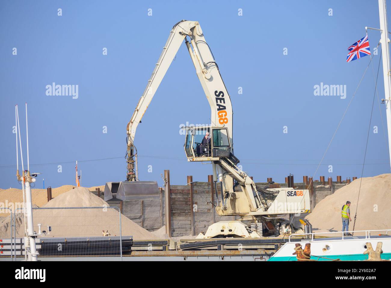 Whitstable, Kent, England, Großbritannien. Terex Fuchs (im Besitz von SEAG8), der Kies auf ein Frachtschiff auf dem EastQuay verlädt Stockfoto
