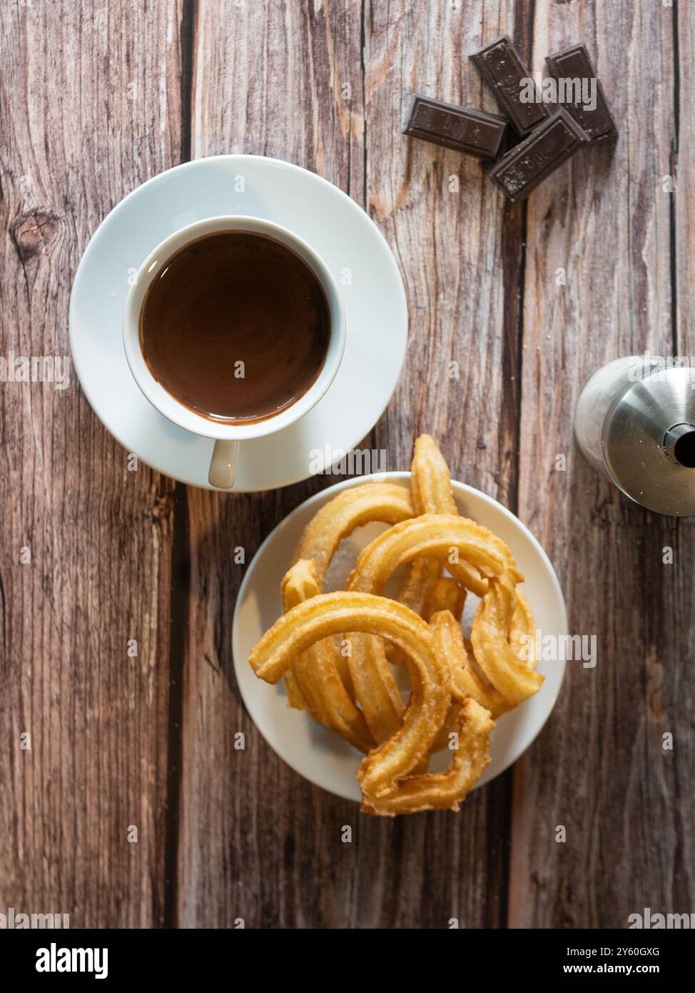 Blick von oben auf ein warmes Schokoladenfrühstück mit Churros auf Holztisch Stockfoto