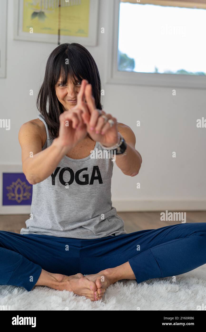 Yoga- und Meditationstrainer sitzen auf einem weichen weißen Teppich, während er eine Mudra aufführt. Stockfoto