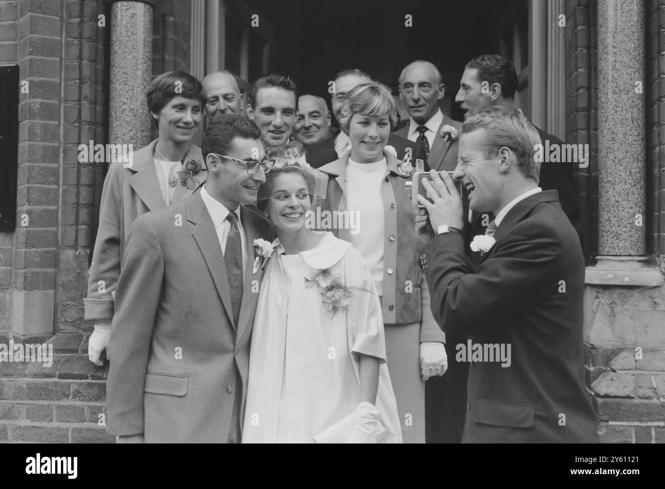 ATHLETIC WEDDING GROUP in Ealing, London, Großbritannien: Der Cine-Fotograf David Jones nimmt eine permanente Aufzeichnung der heutigen Ereignisse im Ealing Registry Office auf, als David Segal Jackie Angove aus Perivale, einem ehemaligen Middlesex-Läufer, heiratete. Auf dem Bild sind auch andere Olympiasieger von links nach rechts: Diane Charles, Peter Radford und Mary Bignal. Die Happy Segals werden in zwei Tagen auf dem Meer sein und in den USA sein, wo Dave weitere drei Jahre an der Furman University studieren kann, obwohl er hofft, für die nächsten Jahre AAA-Meisterschaften und 1962 erneut für die Empire Games zu sein. 14. SEPTEMBER 196 Stockfoto