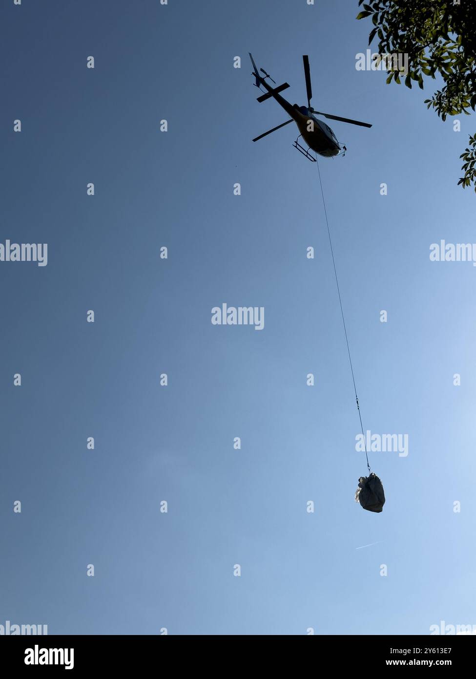 Ein Hubschrauber, der ein Paket in den Bergen des Comer Sees transportiert Stockfoto